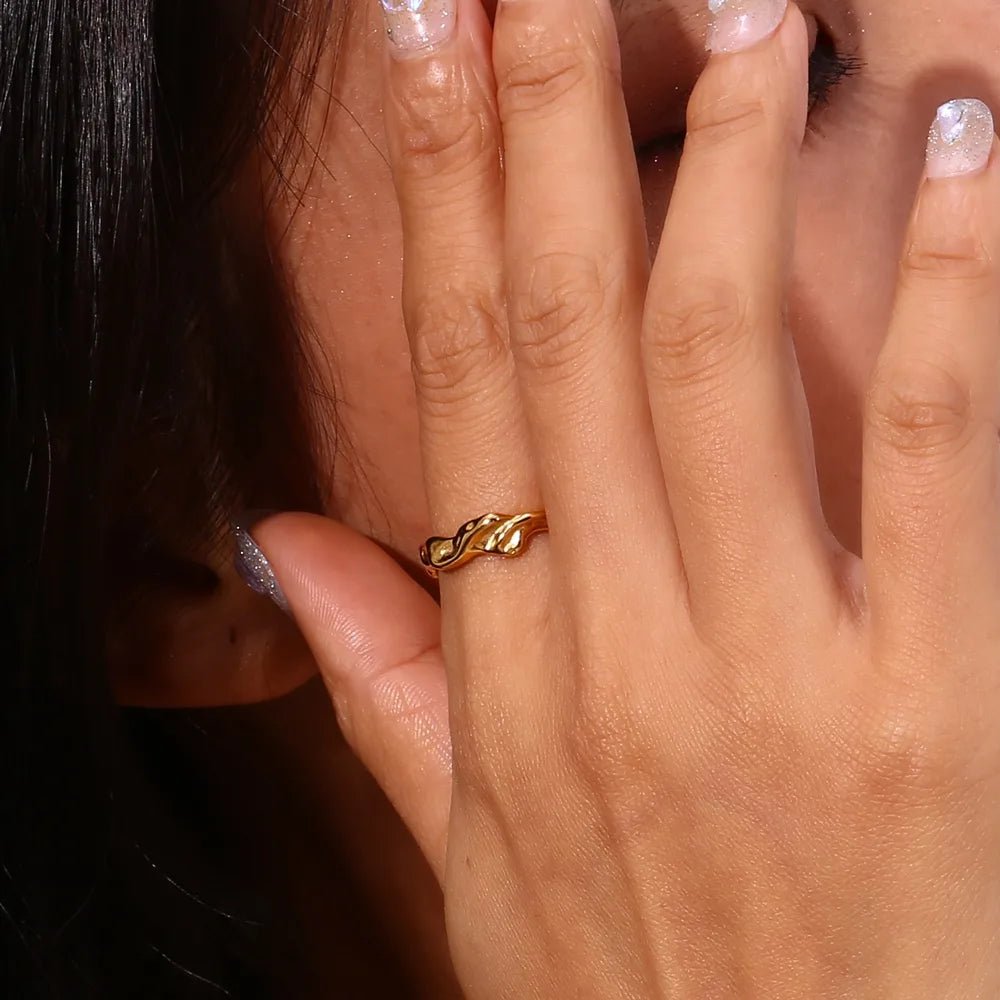 Close-up of a hand wearing a gold ring with a dark background