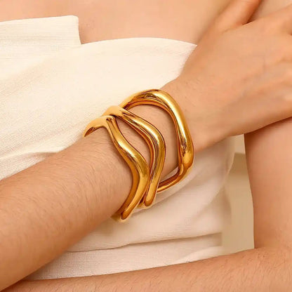 Gold bracelet on a wrist with a neutral background