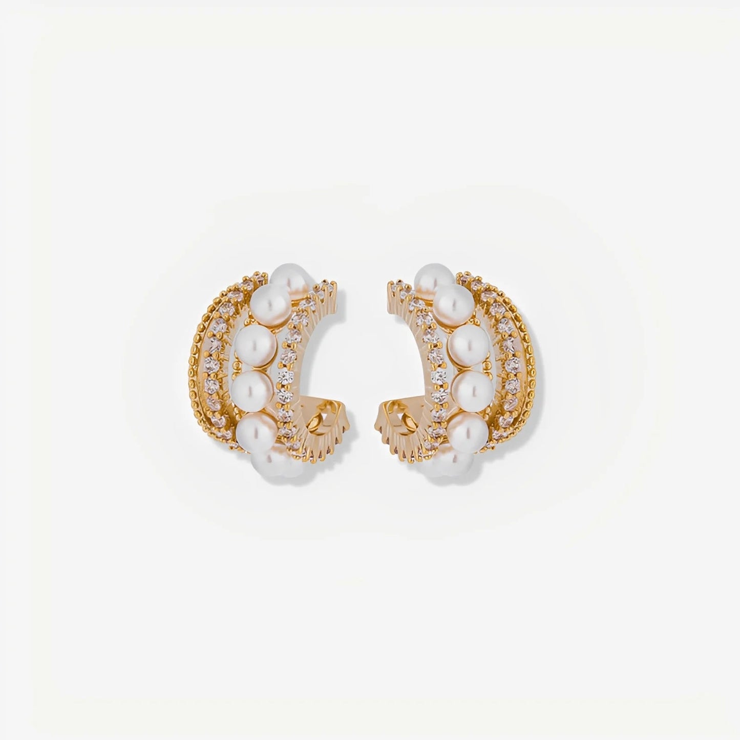 Pair of gold hoop earrings with pearl accents on a light beige background