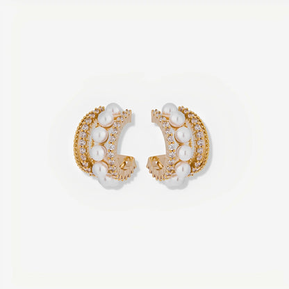 Pair of gold hoop earrings with pearl accents on a light beige background