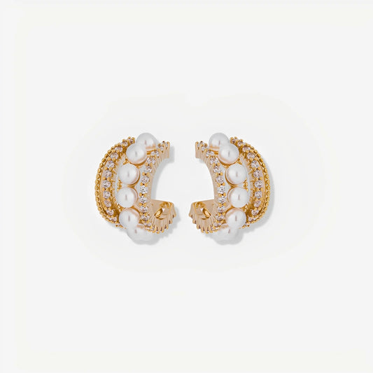 Pair of gold hoop earrings with pearl accents on a light beige background