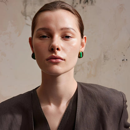 Woman wearing green earrings against a textured beige background