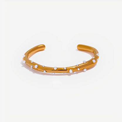 Gold bracelet with small pearls on a light beige background