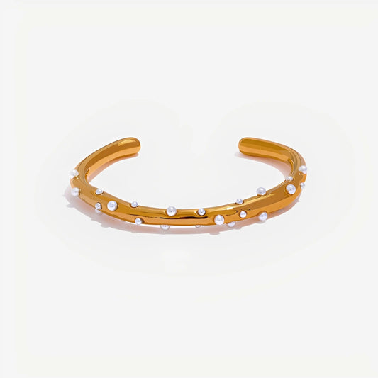 Gold bracelet with small pearls on a light beige background