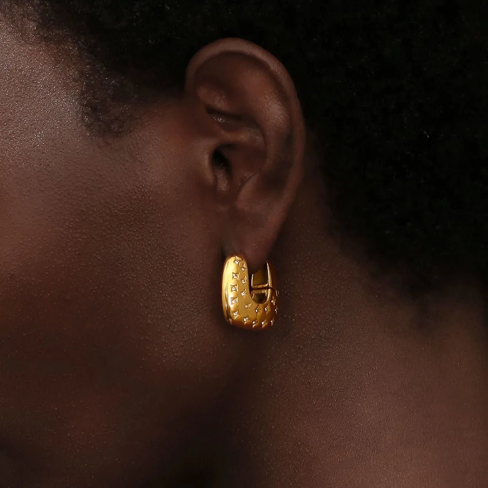 Gold hoop earring worn by a person with a dark skin tone