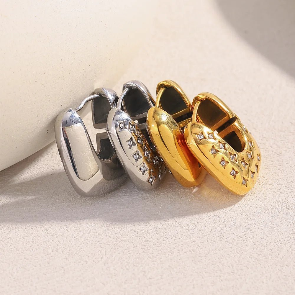 Three pairs of hoop earrings in gold, silver, and a combination of both on a light background.