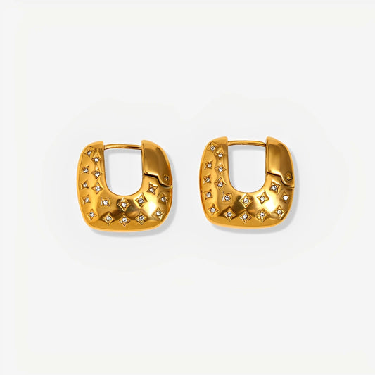 Gold hoop earrings with star-like embellishments on a light gray background